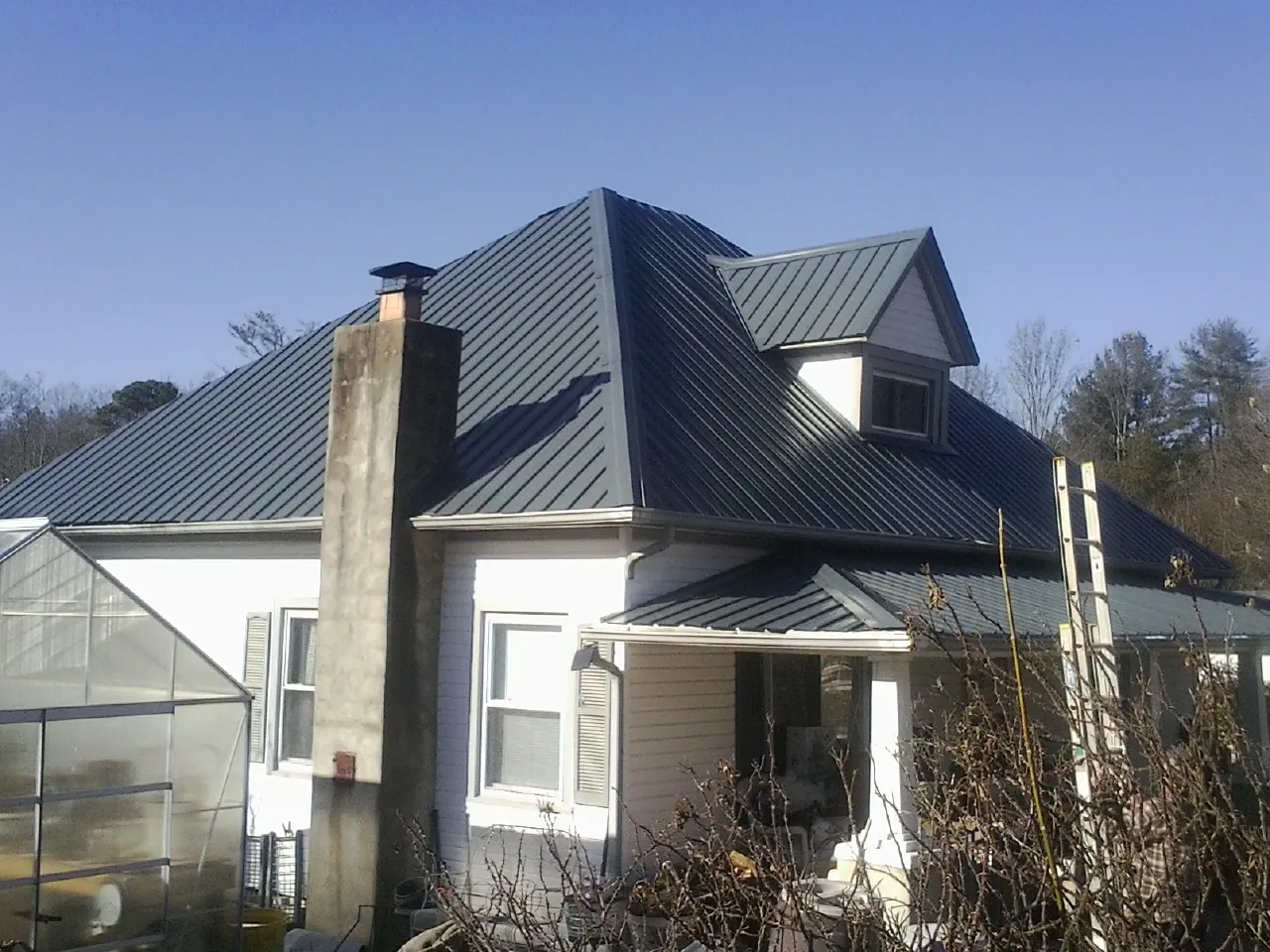 Dark blue standing seam metal roof on a white farmhouse with dormer — Slate & Tile Roof Repair by Roofing Brothers in San Jacinto