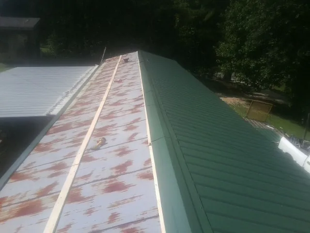 Old rusted panels beside newly installed green metal roofing — Wind Damage Roof Repair by Roofing Brothers in San Jacinto