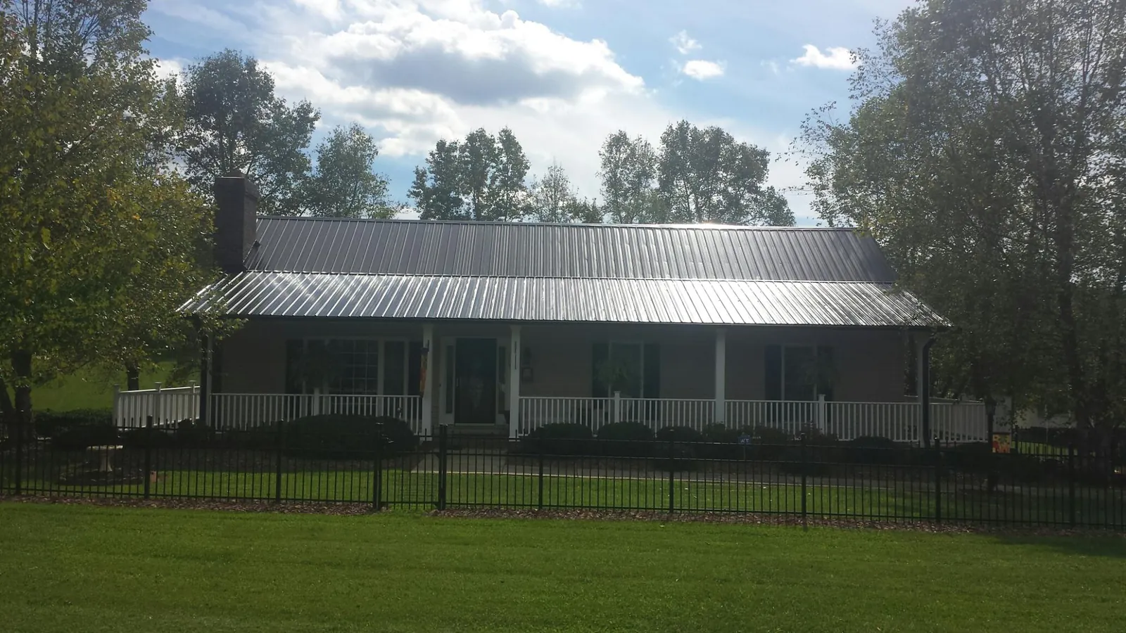 Gray metal roof on a brick ranch with a full width front porch — Gutter Guard Installation work by our crew in San Jacinto